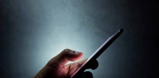 Hand holding a smartphone in dim light.