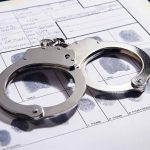 Handcuffs on fingerprint form with fingerprints visible.