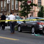 Police and crime scene tape on city street.
