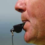 Person blowing a whistle close-up.
