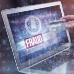 Person holding credit card near laptop displaying "Fraud".