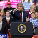 Man speaking at a podium, crowd in background.