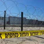Border patrol tape and barbed wire fence.