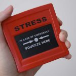Hand holding red stress relief device.