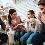 Family discussing with therapist, young girl holding teddy.