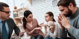Family discussing with therapist, young girl holding teddy.
