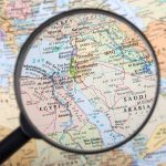 Magnifying glass focused on the Middle East map.