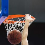 Hand dunking a basketball through a hoop.