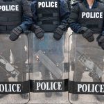 Police officers in riot gear holding shields.