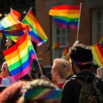crowd of people waving rainbow colored flags