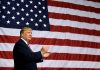 Man clapping in front of American flag backdrop