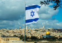 Israeli flag flying over Jerusalem cityscape and Dome.