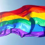 Rainbow flag waving against a clear sky