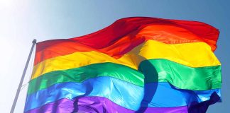Rainbow flag waving against a clear sky