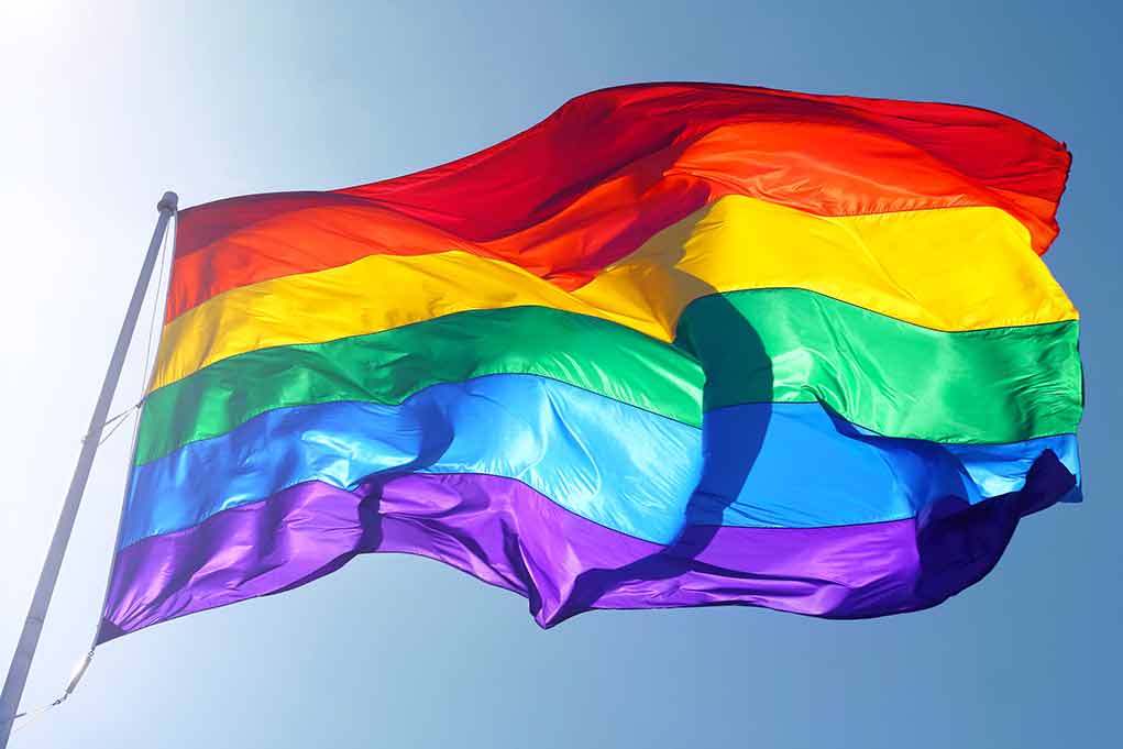 Rainbow flag waving against blue sky