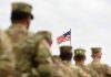 Soldiers in formation with American flag in background