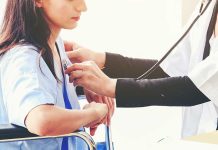 Doctor examining patient with stethoscope in hospital