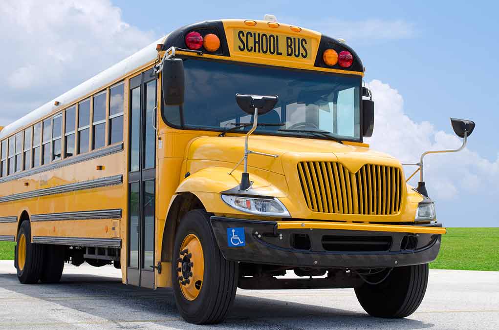 Yellow school bus parked on pavement under blue sky