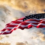 American flag waving against a dramatic cloudy sky