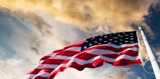 American flag waving against a dramatic cloudy sky