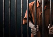 Person in orange uniform behind prison bars