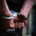 Hands in handcuffs behind back close up