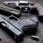 Pistols with scattered bullets on a dark surface