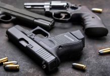 Pistols with scattered bullets on a dark surface