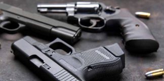 Pistols with scattered bullets on a dark surface