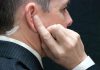 Man wearing an earpiece touching his ear
