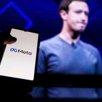 Hand holding phone displaying Meta logo screen