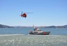 Helicopter flying above Coast Guard boat on water