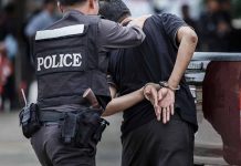 Police officer arrests handcuffed person