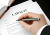 Hand holding pen filling out lawsuit form
