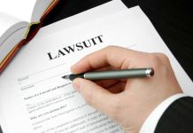 Hand holding pen filling out lawsuit form