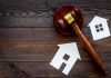 Gavel and house cutouts on wooden table