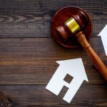 Gavel and house cutouts on wooden table