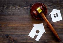 Gavel and house cutouts on wooden table