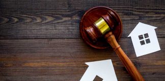 Gavel and house cutouts on wooden table