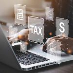 Person typing on laptop with tax related icons displayed