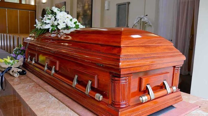 763141204 featured image Wooden casket with white flowers in a funeral home