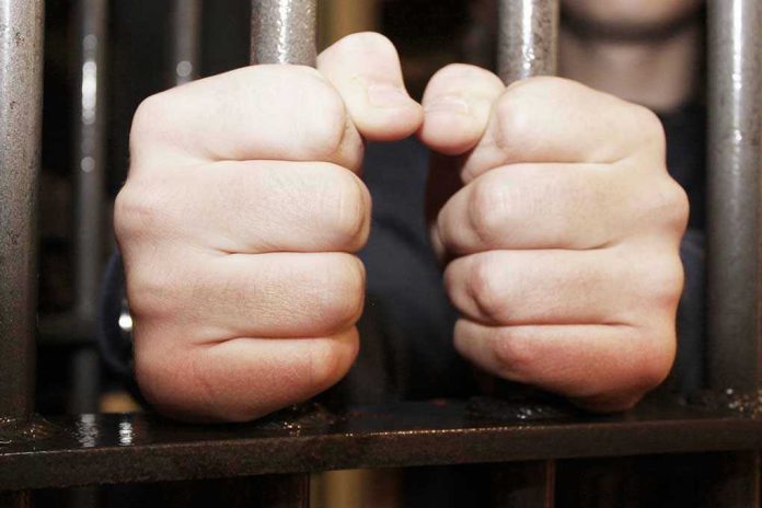 108342344 Hands gripping jail cell bars tightly