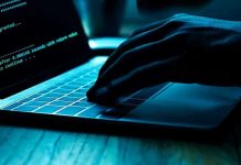 Hand typing on laptop with code on screen.