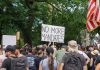 Crowd holds "No More Mandates" sign at protest.