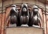 Three wise monkeys statue on a brick building