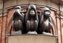 Three wise monkeys statue on a brick building