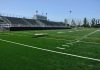 Empty football field with bleachers in background