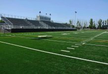 Empty football field with bleachers in background