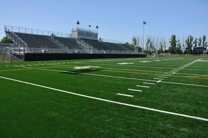 Empty football field with bleachers in background