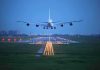 An airplane approaching the runway at night with landing lights illuminated